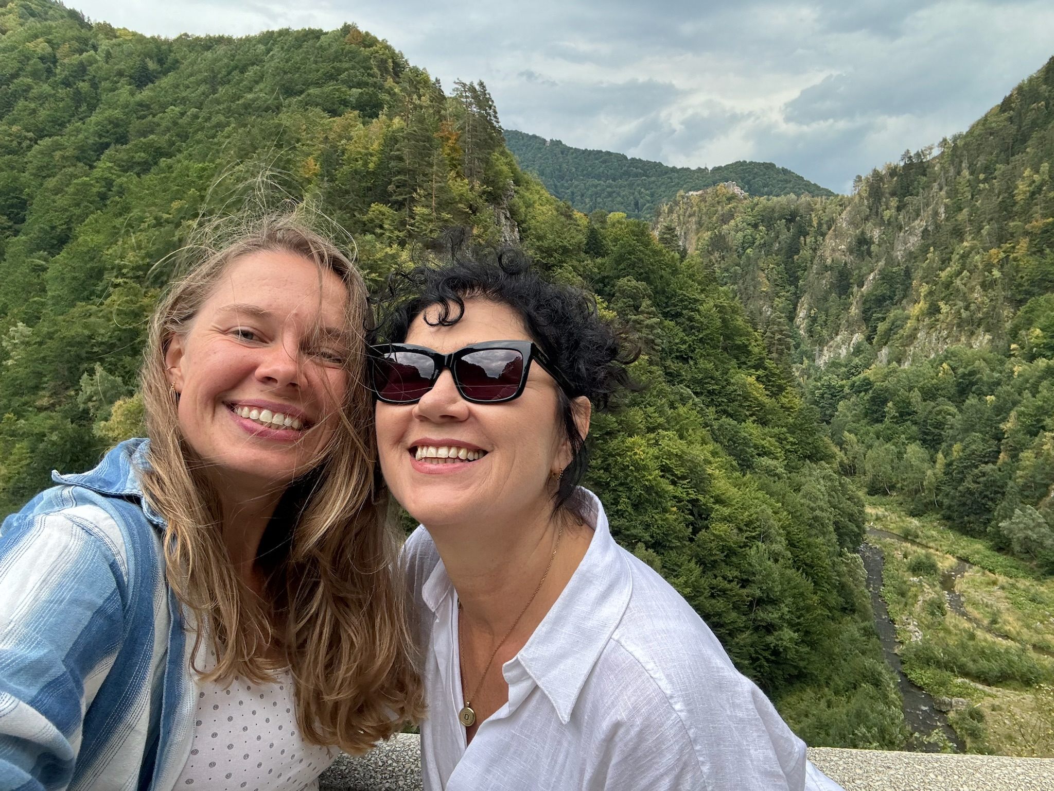 Hier sieht man im Hintergrund, wenn auch etwas weit entfernt die Burg Poenari, die richtige Burg von Dracula. davor stehen zwei reisende Frauen die glücklich sidn über ihren Fund während der Transsilvanien Reise.