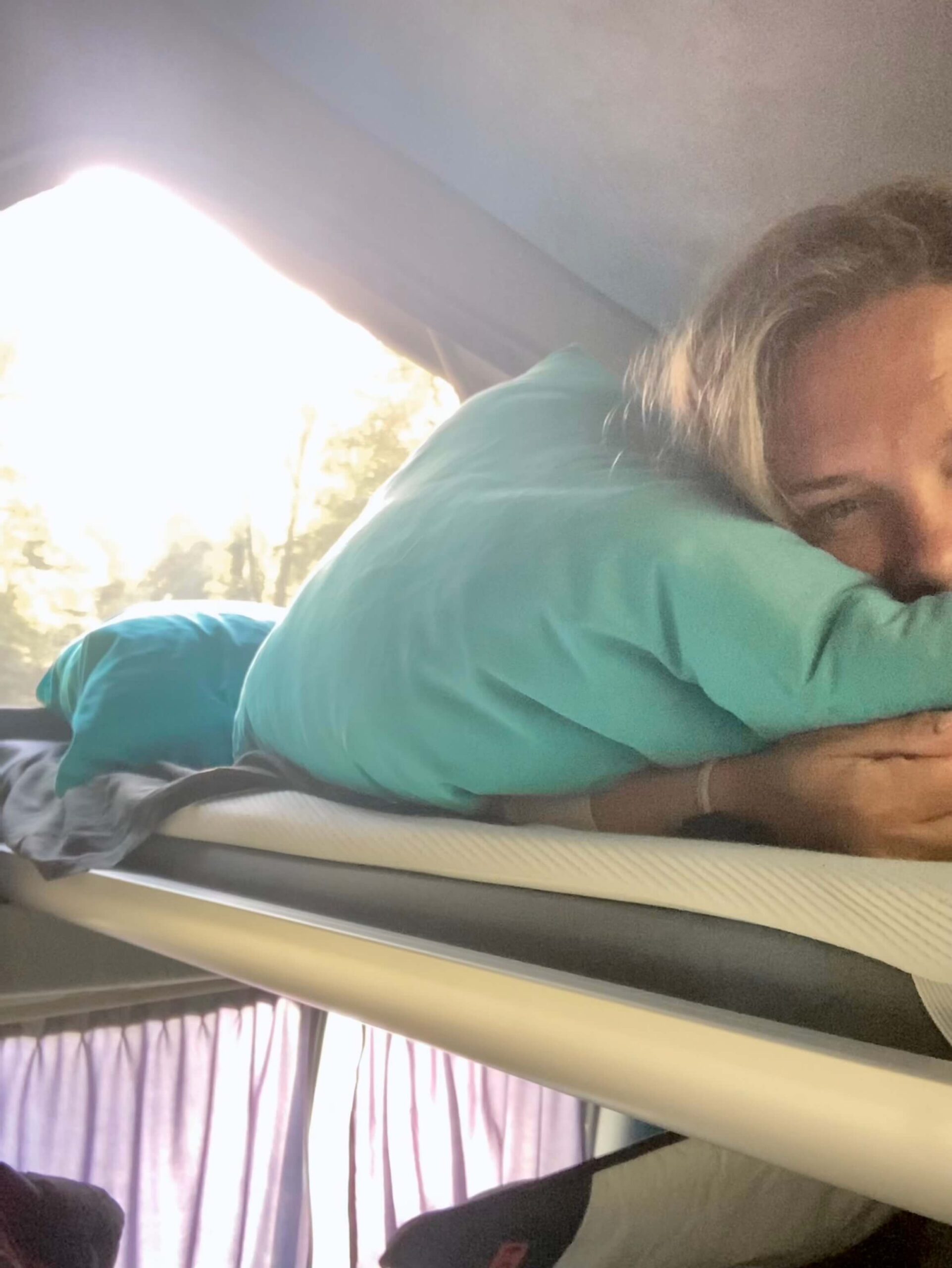 Frau liegt in einem Dachbett von einem Van.