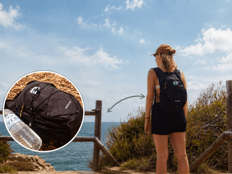 Auf dem Bild sieht man eine Frau am Meer stehen. Sie trägt eine kappe und einen kleinen Rucksack, den sogenannten Tagesrucksack. Ihr Tagesrucksack ist schwarz und klein.